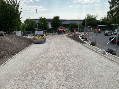 A steam roller has flattened a large area gravel, ready to get tarmac.