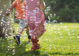 Childrenr running through grass with bubbles