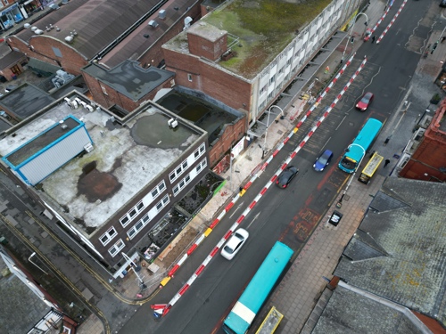 An aerial view of Eastbank Street, with visible red and white fencing, but the road is still open to cars. - February 2025