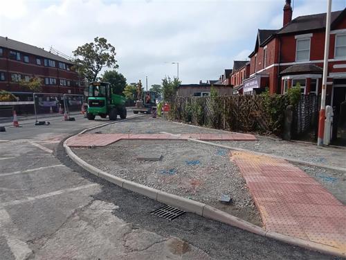 A photo of a corner of a crossing, with tactile paving laid down but the pavement isn't finished with gravel.