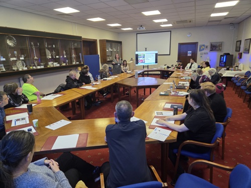 Meeting in the Committee Room with members of the group sat facing the screen where a presentation is being given