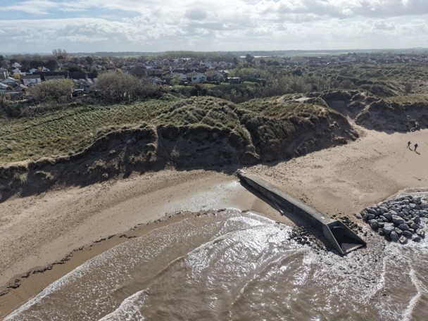 Photo showing erosion to the dunes and a difference in beach level on either side of the outfall