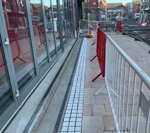 A progress picture of Market Street, showing small white tiles for drainage at the end of the new pink tiles - February 2025